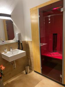 a bathroom with a sink and a red shower at Land-Hotel Am Wald Garni in Greiz