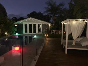 a pool with a bed and a table with lights at Woy Woy Staycation - Heated Pool & Hot Tub & BBQ & Pizza Oven & Arcade Game & Pool Table in Woy Woy