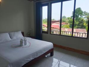 a bedroom with a bed and a large window at Vang Vieng Champa Hotel in Vang Vieng
