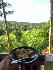 una persona sosteniendo un plato con comida en una mesa en Serenity Lodge Tetebatu Lombok, en Tetebatu
