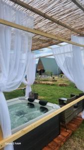 una bañera de hidromasaje en un patio trasero con cortinas blancas en olive garden farm en Ulcinj
