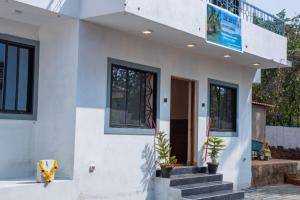 a white house with stairs and a balcony at DE 28:11 GUEST HOUSE in Mapusa