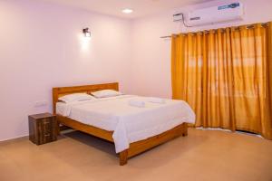 a bedroom with a bed and a yellow curtain at DE 28:11 GUEST HOUSE in Mapusa