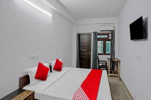 a bedroom with a white bed with red pillows at OYO Hotel Grand Shiva in Noida