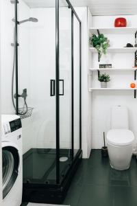 uma cabina de duche em vidro na casa de banho com uma máquina de lavar roupa em City Center Maakri Apartment em Talin