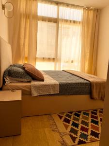 1 dormitorio con 1 cama con ventana y alfombra en Port Ghalib Apartments, en Port Ghalib