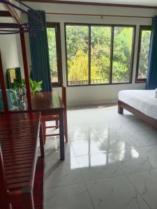 a bedroom with a bed and a table and windows at Dokchampa Hotel in Vang Vieng