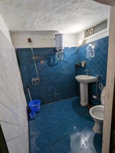 a blue tiled bathroom with a toilet and a sink at Resort Blue Lotus in Almora