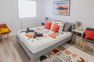Schlafzimmer mit einem Bett mit roten und orangefarbenen Kissen in der Unterkunft Aux portes de Bordeaux/\Les Carrelets/\MindUrGuest in Lormont