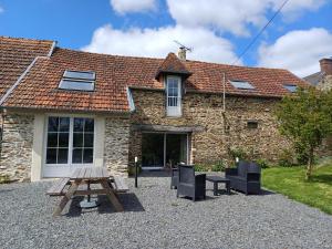 a picnic table and chairs in front of a building at Gite de la Motte in Litteau