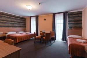 Cette chambre d'hôtel comprend deux lits, une table et des chaises. dans l'établissement Hotel Pod Figurą, à Ogrodzieniec