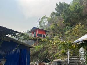 una casa roja en la cima de una colina en Langhali Agricultural Homestay, en Pokhara