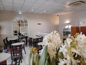 a dining room with tables and chairs and white flowers at Hôtel de Paris in Lourdes