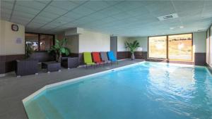 a large swimming pool with colorful chairs in a building at Appartement 4 personnes avec piscine, wifi, garage in Besse-et-Saint-Anastaise