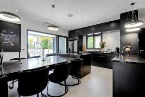 a large kitchen with black counters and black chairs at Villa Vice City -proche Eurexpo/Groupama stadium/LDLC Arena in Chamagnieu