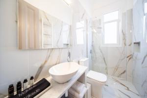 a white bathroom with a sink and a toilet at Oikia Tripodon in Athens