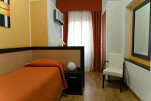 a bedroom with a orange bed and a chair at Albergo San Lorenzo in Grosseto