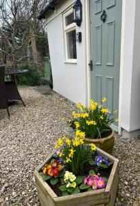 a garden with flowers in a wooden box next to a door at Cosy Cotswold Cottage with garden Quenington near Bibury in Quenington