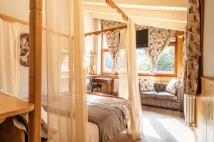 1 dormitorio con cama con dosel y sofá en La Tana dell'orso Hotel & SPA en Ponte di Legno