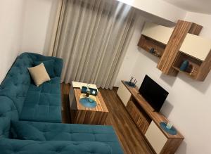 a living room with a blue couch and a table at Oceans Apartman in Dobra Voda