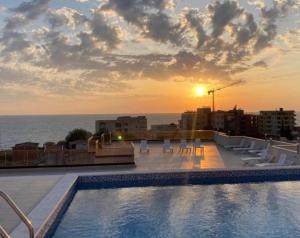 a pool on the roof of a building with the sunset at Oceans Apartman in Dobra Voda