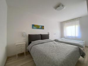 a white bedroom with two beds and a window at WoodenKey Asiago grazioso appartamento in centro in Asiago