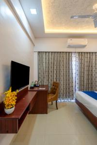 een hotelkamer met een televisie, een bed en een bureau bij StayBird - Divine Suites, Business Hotel, Kharadi in Pune
