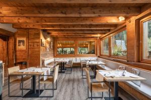 un ristorante con pareti e tavoli in legno e finestre di La Tana dell'orso Hotel & SPA a Ponte di Legno