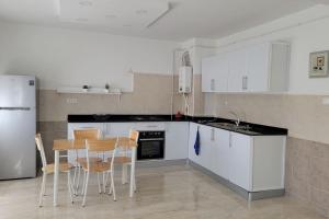 uma cozinha com armários brancos e uma mesa e cadeiras em Joli appartement au centre em Annaba