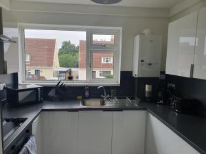 uma cozinha com um lavatório e uma janela em Sunny Apartment In Cheltenham em Cheltenham