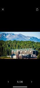 a picture of a building with mountains in the background at Apartamentul Verde Silver Mountain Poiana Brașov in Poiana Brasov