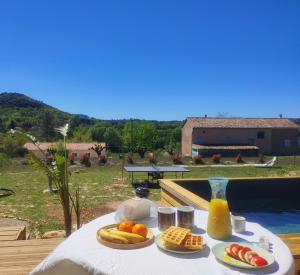 a table with plates of fruit and a bottle of juice at Aux amoureux de Provence in Fox-Amphoux