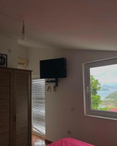 a bedroom with a flat screen tv on the wall and a window at Kuća Radović in Budva