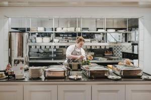 a woman standing in a kitchen preparing food at Buchnas Landhotel Saarschleife in Mettlach