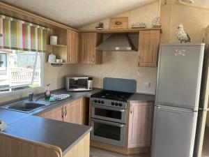 a kitchen with a refrigerator and a stove top oven at Pets Stay free 2 bedroom caravan at heacham beach in Hunstanton