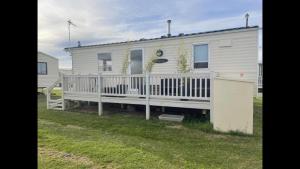 a white house with a porch and a fence at Pets Stay free 2 bedroom caravan at heacham beach in Hunstanton