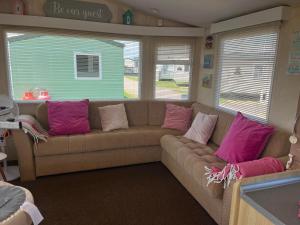 a living room with a brown couch with pink pillows at Pets Stay free 2 bedroom caravan at heacham beach in Hunstanton
