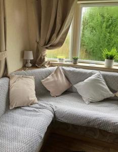 a couch with pillows in a room with a window at Blue Beach Retreats Ltd in Mablethorpe