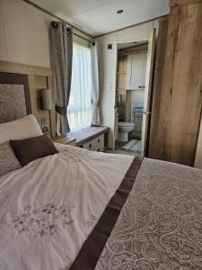 ein Schlafzimmer mit großem Bett und ein Badezimmer in der Unterkunft Premium 2 Bedroom Caravan with Free Wifi in Hunstanton
