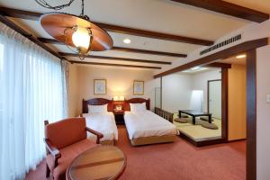 a bedroom with two beds and a chair and a table at Sun Members Hirugano in Gujo