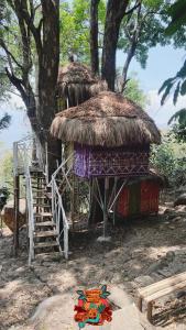 a small hut with a staircase next to a tree at Woodman Hideout in Kanthalloor