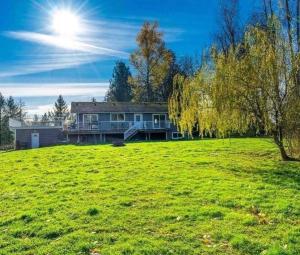a house on a green field with the sun in the sky at 43 Ave Farm House Langley in Aldergrove