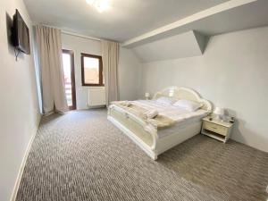 Schlafzimmer mit einem weißen Bett und einem TV in der Unterkunft Casa Polen Comarnic in Comarnic