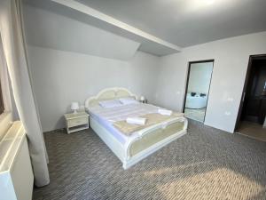 ein weißes Schlafzimmer mit einem Bett und einem Spiegel in der Unterkunft Casa Polen Comarnic in Comarnic