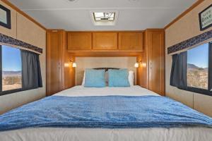 een slaapkamer met een groot bed met blauwe kussens bij JT Village Campground - Casa Pequena in Joshua Tree