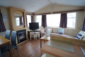 a living room with a couch and a tv at pets stay free 3 bedroom caravan at heacham beach in Heacham