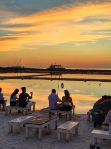 mensen zitten op bankjes op het strand bij zonsondergang bij Casa vacanze VIA ROMA 57 in Marsala