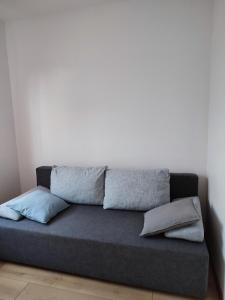 a couch against a white wall with pillows on it at Mieszkanie z ogrodem in Gdańsk