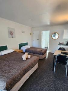 um quarto de hotel com duas camas, uma secretária e uma mesa em Bulls Motel & Holiday Park em Bulls