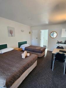 a hotel room with two beds and a desk and a table at Bulls Motel & Holiday Park in Bulls